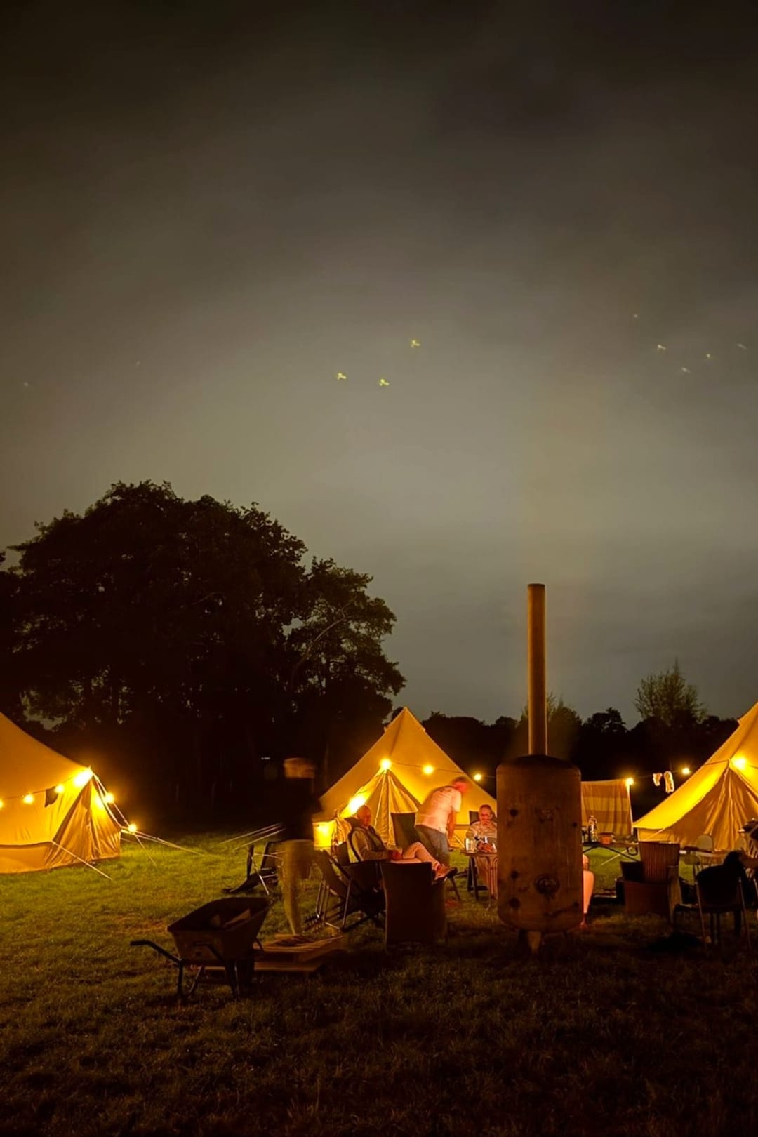 Belltenten van Honeybell met lichtsnoeren rond een vuurkorf, laat op de avond